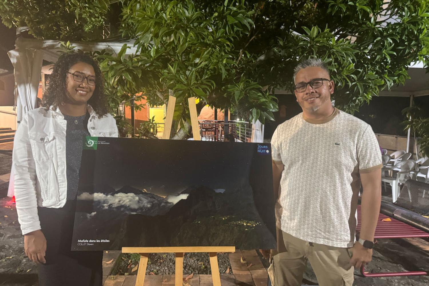 Steven Collet et sa compagne entourent la photo "Mafate dans les étoiles" © Parc national de La Réunion